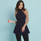 Model wearing the Ines Polka Dot Top by Shopise featuring a high halter neckline, ruched waist, and flared peplum hem in navy with white dots